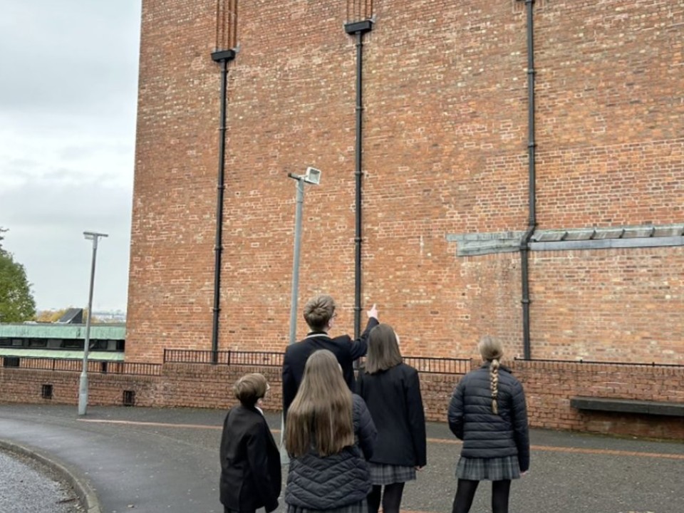 Pupils in school uniform looking up at a tall brick building.