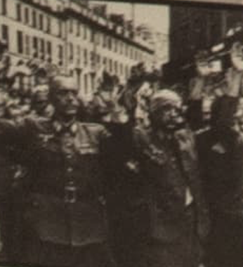 Black and white photograph of German soldiers with their hands raised in surrender in a city street.